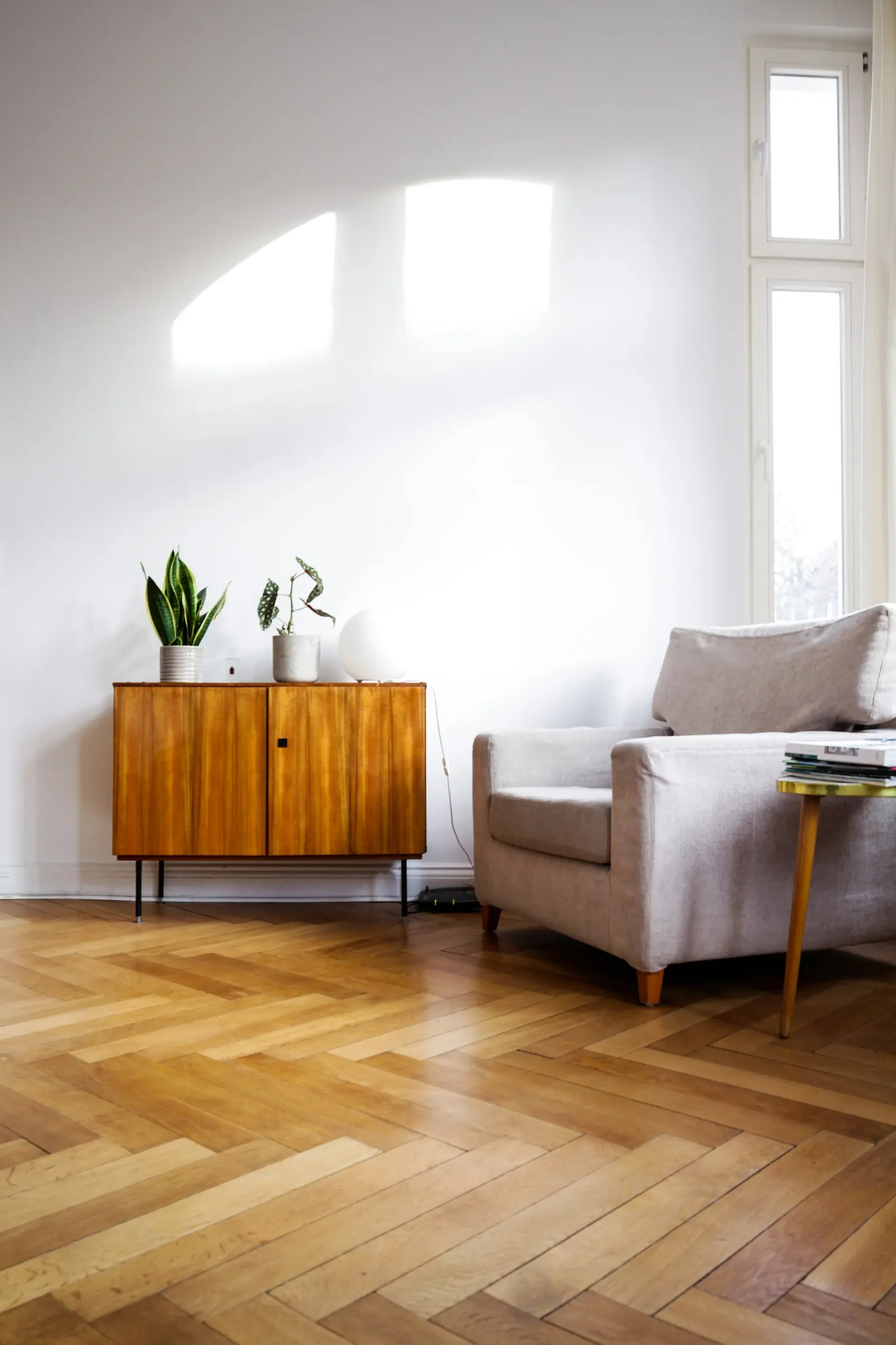 Heller Wohnraum mit Fischgrätparkett und Sideboard